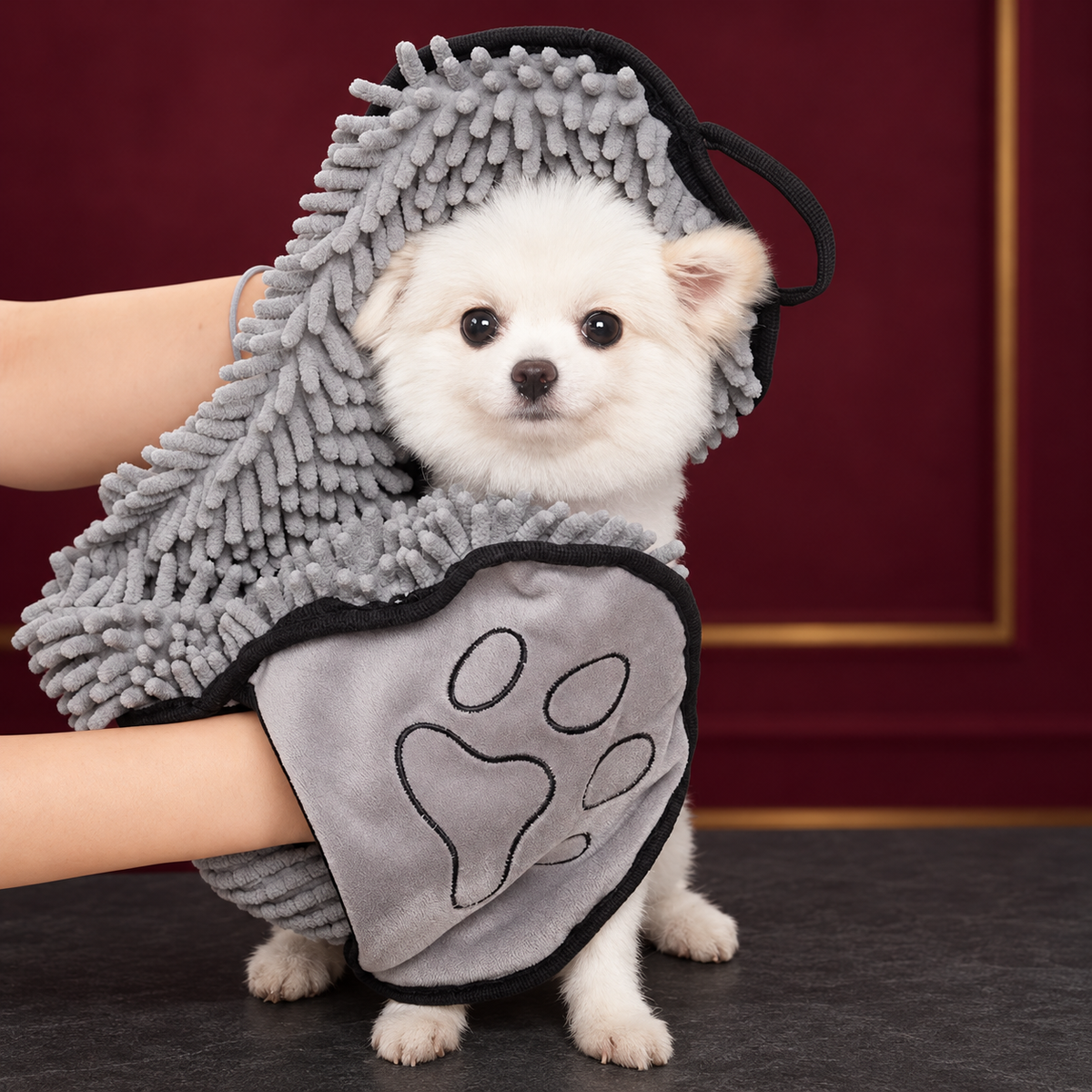 Grey pet drying towel with hand pockets used to dry a small white dog