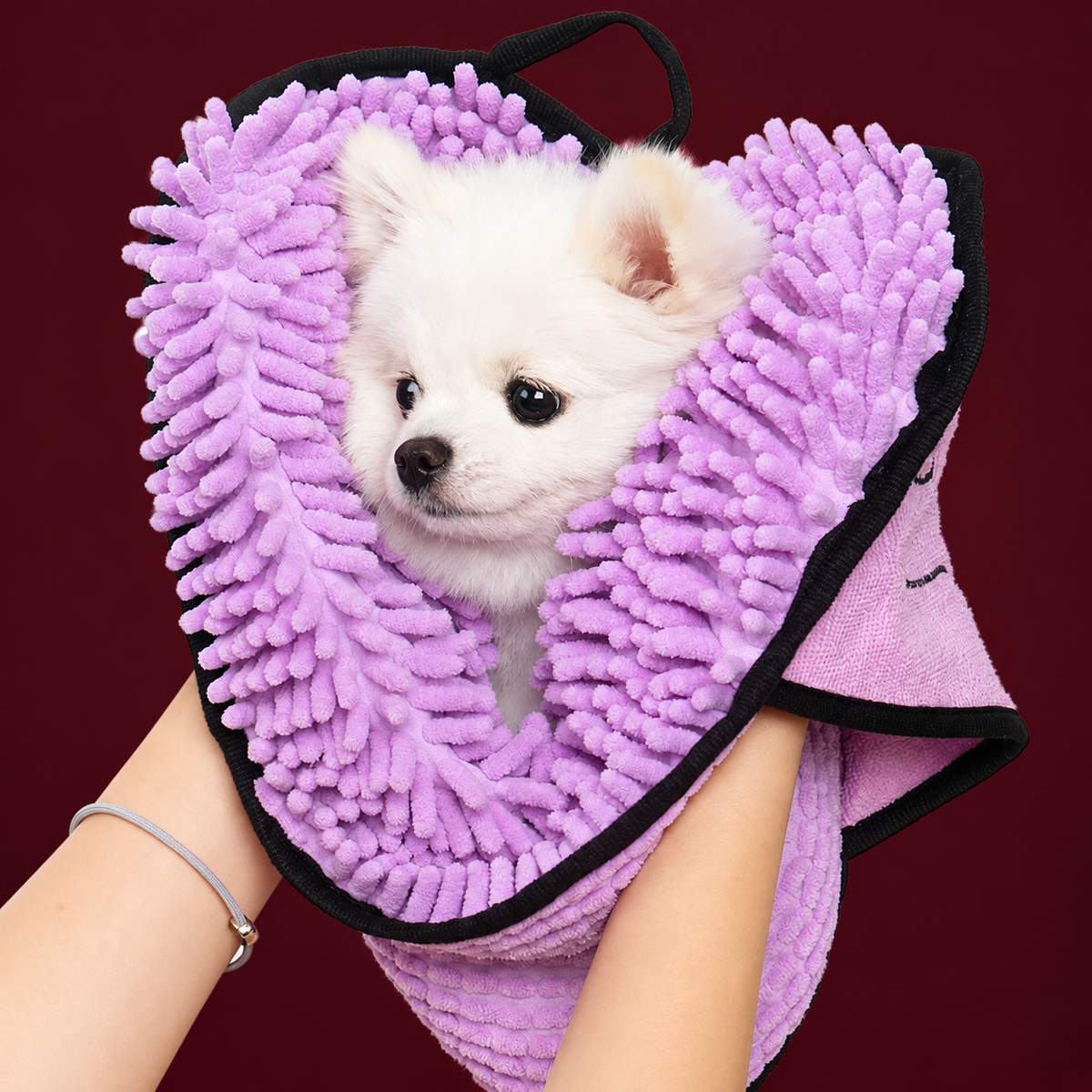 Purple pet towel with hand pockets used to dry a small white dog